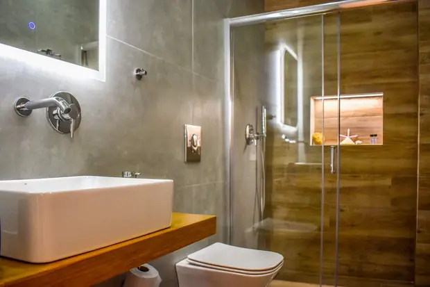 Bathroom with a basin on an oak counter and a glass shower