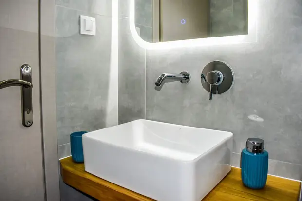The basin beneath a backlit mirror