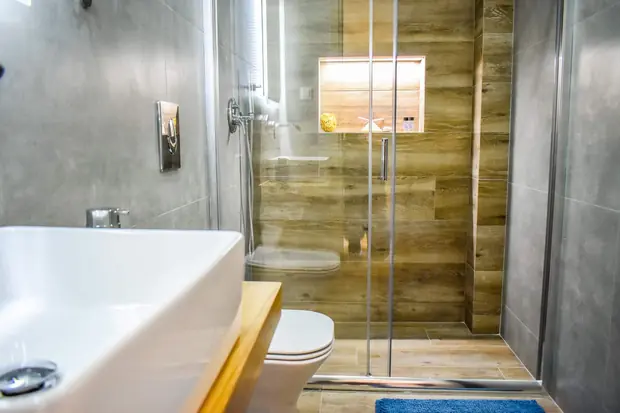 Glass shower with a lit niche in the wood-effect wall