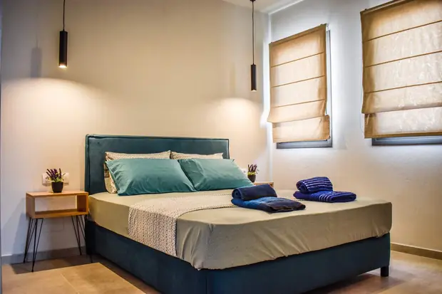 Bedroom with a double bed, teal headboard and roman blinds