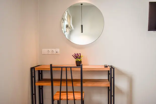 Wood and steel desk under a round mirror